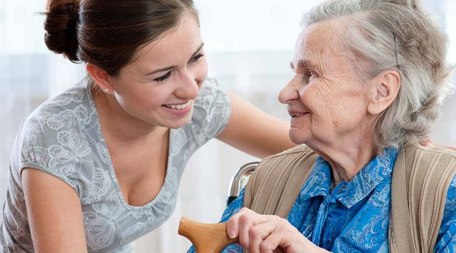 Our Highly Trained In-Home Health Provider And Care Taker Helps A Woman With Alzheimer'S Use A Cane
