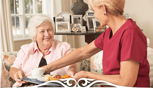 In-Home Care Giver Serving Lunch To Lady With Dementia