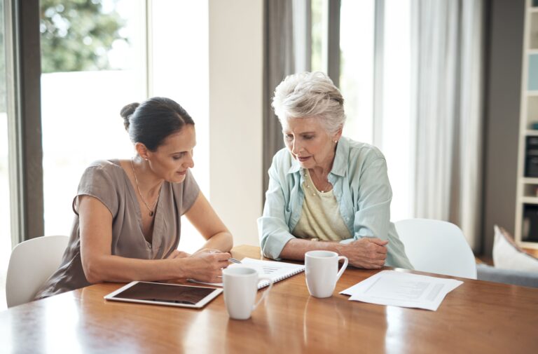 An older woman and her daughter discuss choosing the best home care agency with long-term care insurance as they review the policy together.