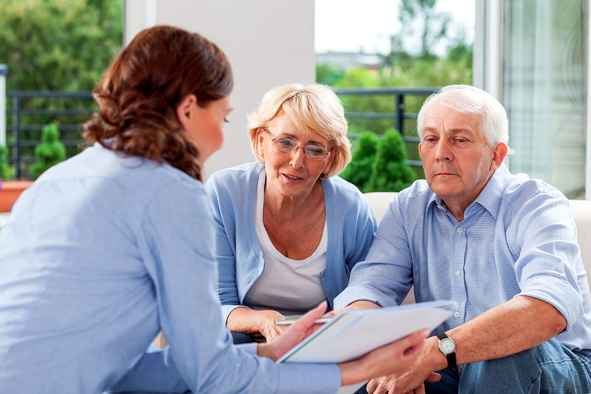 A woman explains some of the misconceptions about long-term care insurance to an older couple.