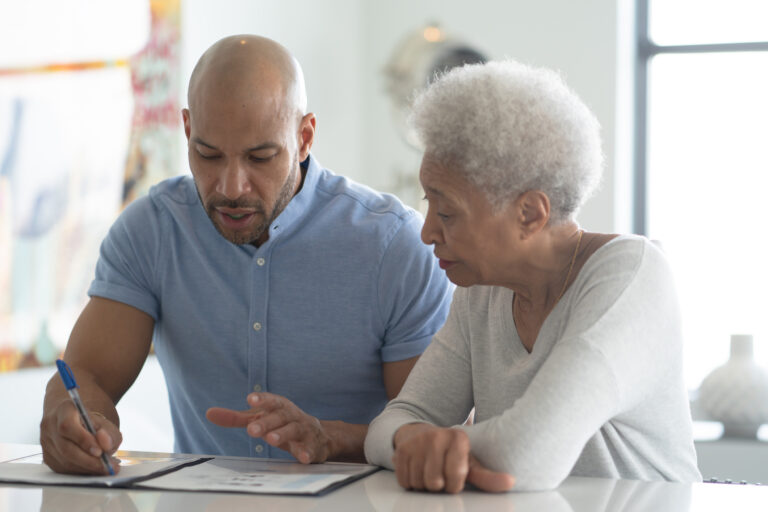 A man explains the basics of long-term care insurance for home care to an older woman.